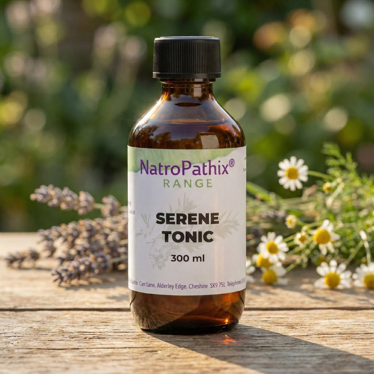 A bottle of Serene Tonic Tincture - 200/300ml rests on a wooden table with flowers in the background, showcasing its calming benefits.