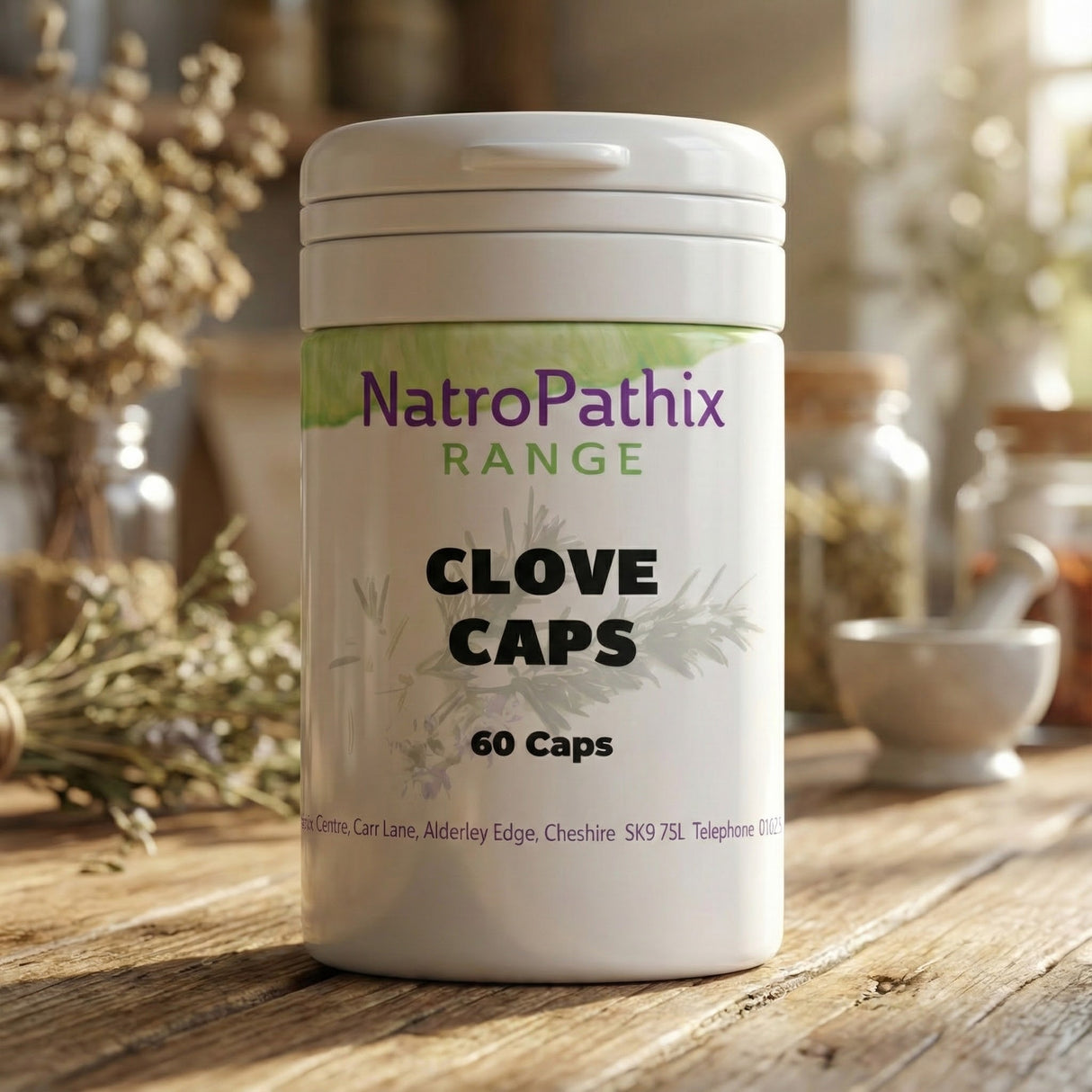A white bottle labeled "Clove tablets - 120 capsules" sits on a wooden table with herbs in the background, highlighting these potent clove supplements often used for parasite cleanse and natural anti-inflammatory support.