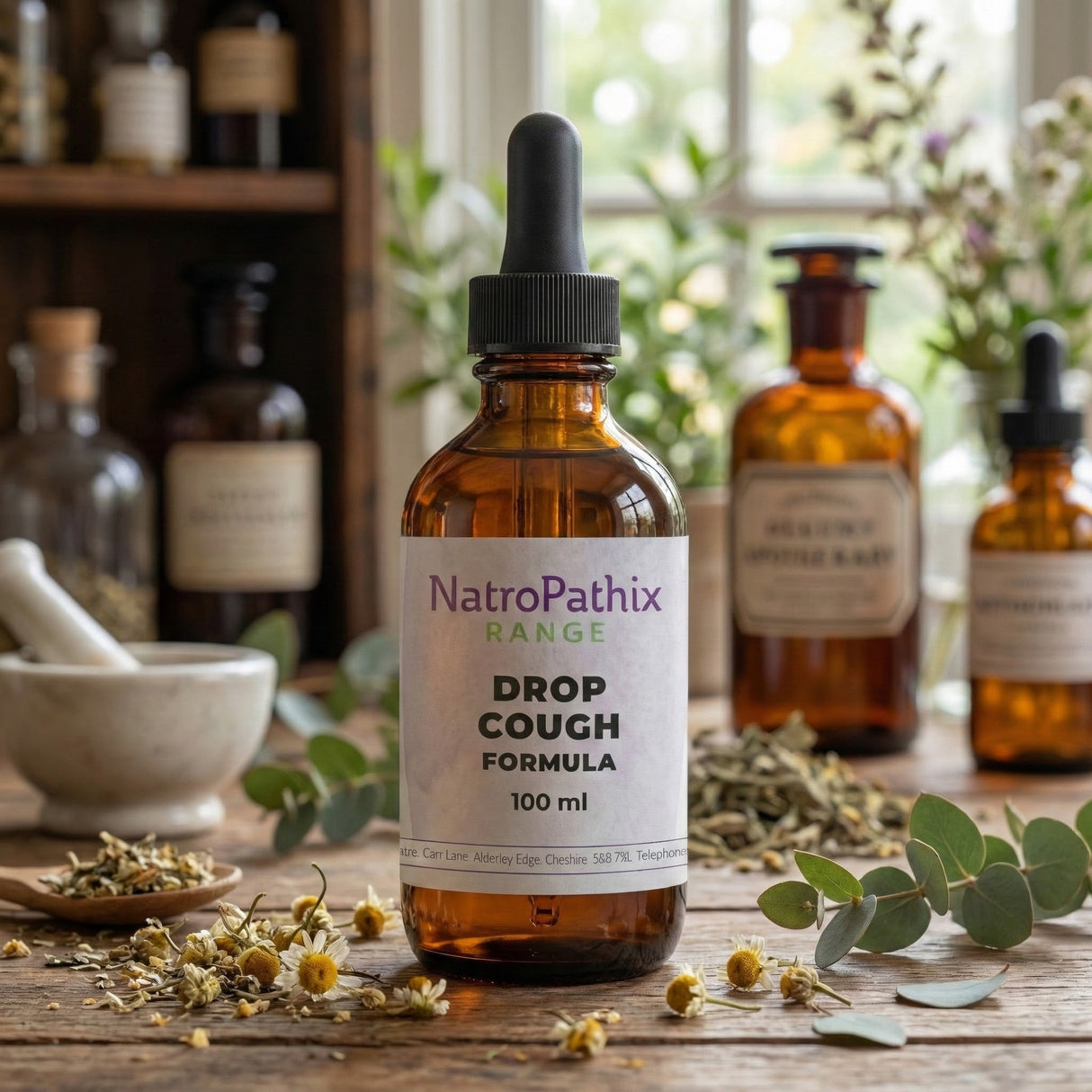 A bottle of Drop Cough Tincture - 100ml, recognized for its expectorant benefits, rests on a wooden table surrounded by herbs and apothecary items.