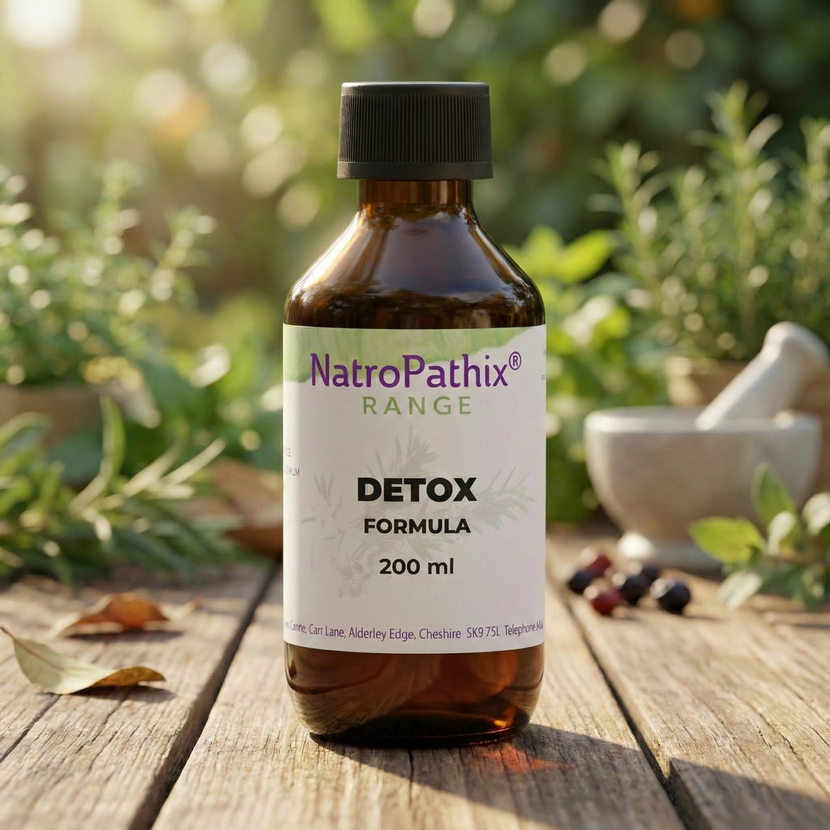 A brown bottle labeled "Detox Formula - 200ml," an herbal tincture for liver support, rests on a wooden surface outdoors.