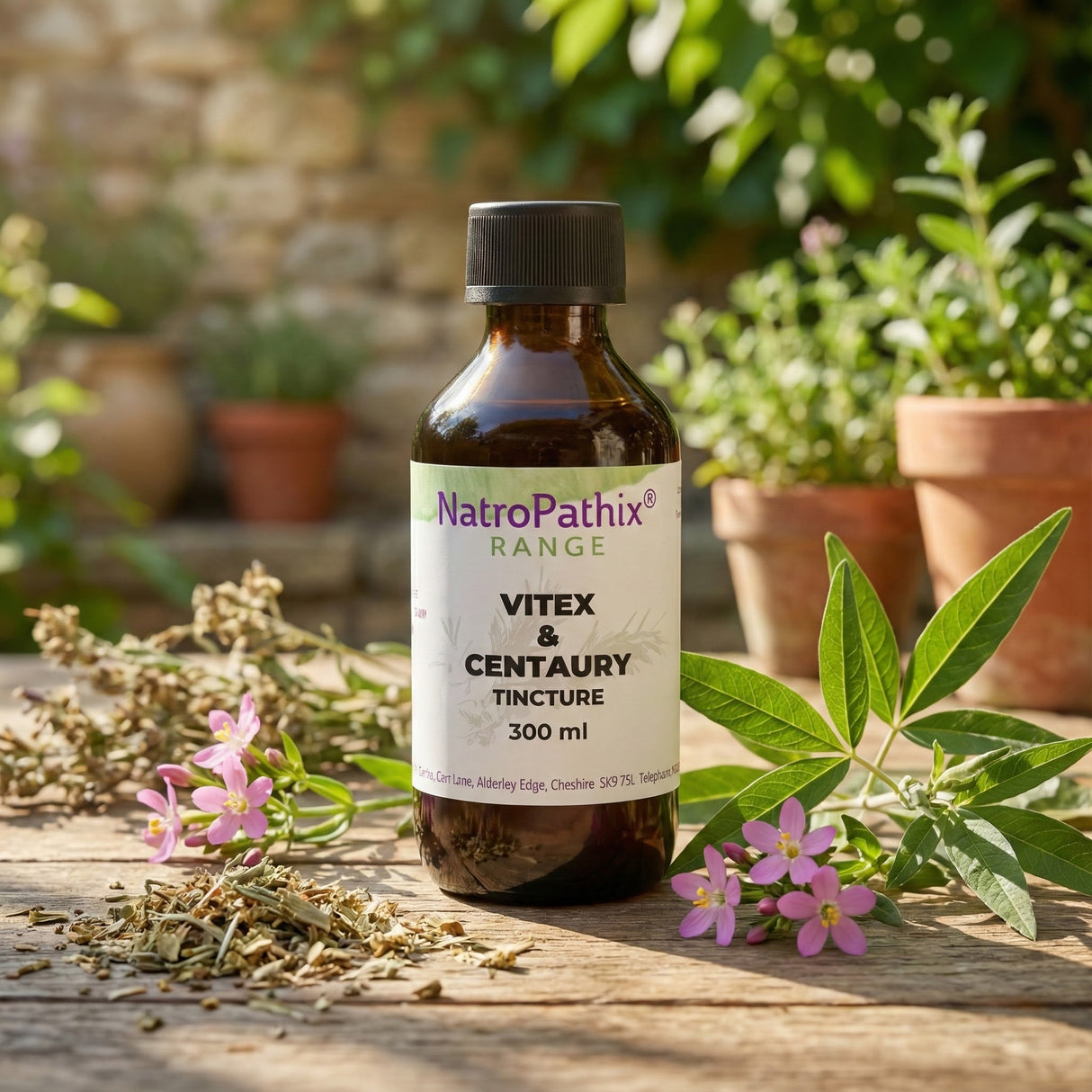 A bottle of Vitex and Centaury Tincture - 200/300ml sits on a wooden table with herbs and potted plants, specially formulated to support hormonal balance and provide relief from menopausal symptoms.