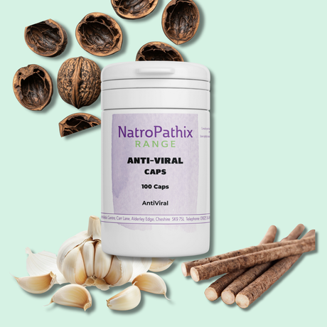 A bottle of Anti-Viral Herbs - 150 Capsules, formulated to support the immune system, is surrounded by walnuts, garlic cloves, and licorice roots.