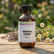 A bottle of Serene Tonic Tincture - 200/300ml rests on a wooden table with flowers in the background, showcasing its calming benefits.