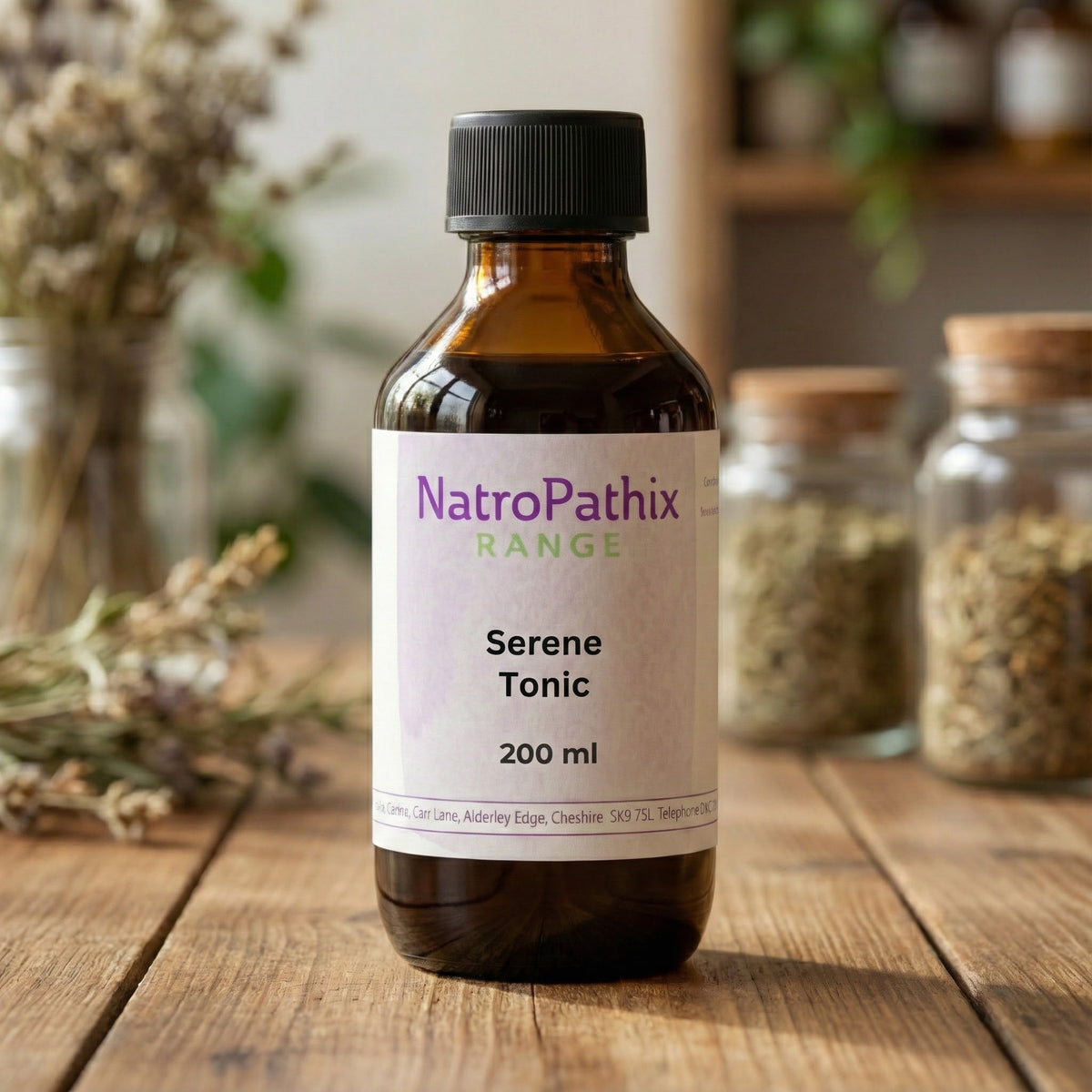 A brown bottle labeled "Serene Tonic Tincture - 200ml" rests on a wooden table, surrounded by dried herbs, showcasing its gentle anti-spasmodic formula for natural anxiety relief.