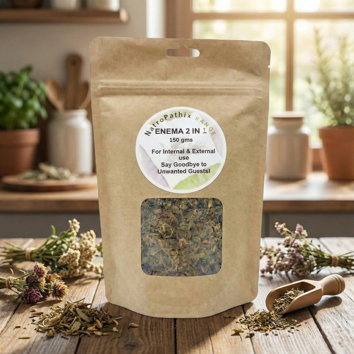 A brown paper bag of Enema 2-1 Tea - 150gms sits on a wooden table, surrounded by dried flowers and a scoop, offering a natural way to support parasite cleansing.